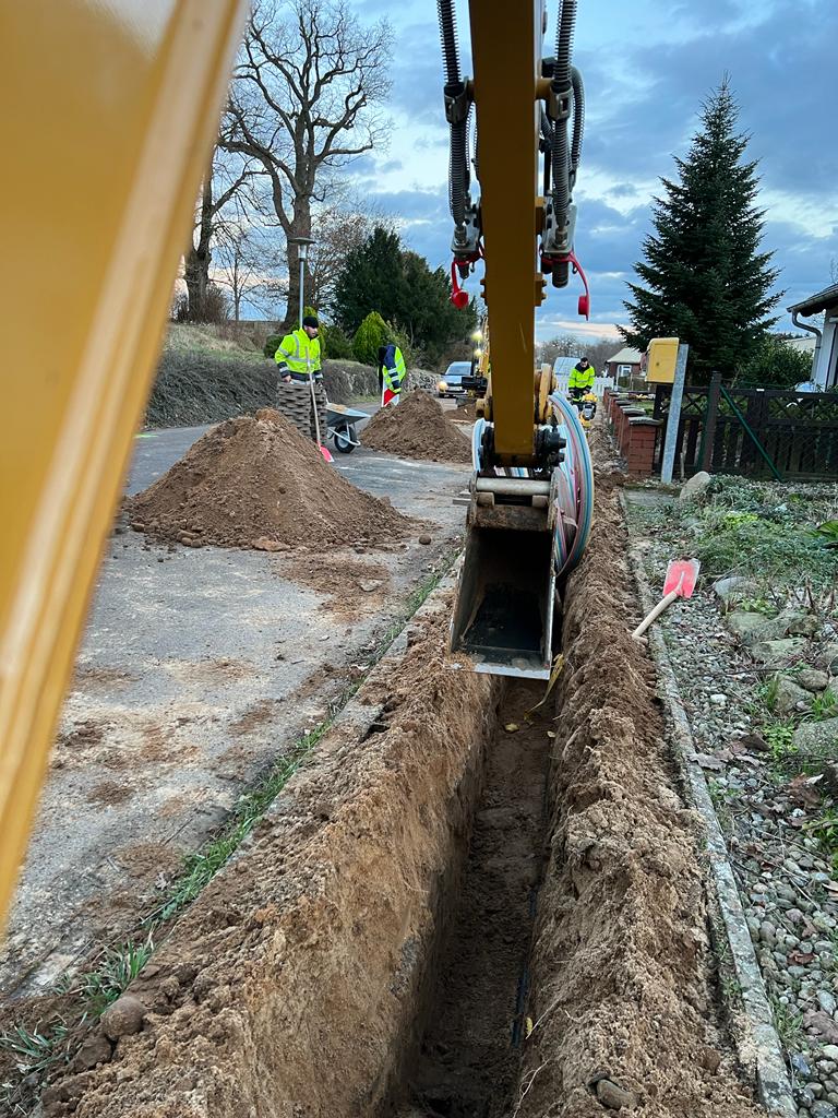 Mitarbeiter und Baufahrzeuge der GeBA Baustein GmbH bei der Verlegung von Glasfaserkabeln