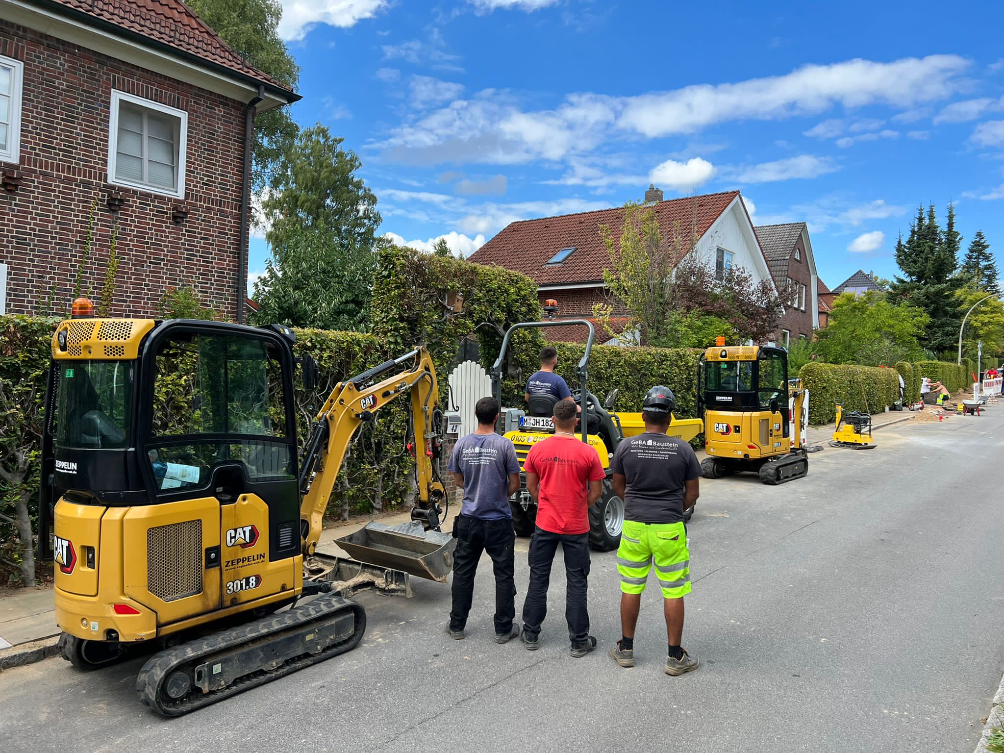 Mehrere Mitarbeiter und Baufahrzeuge der GeBA Baustein GmbH bei Straßenbauarbeiten